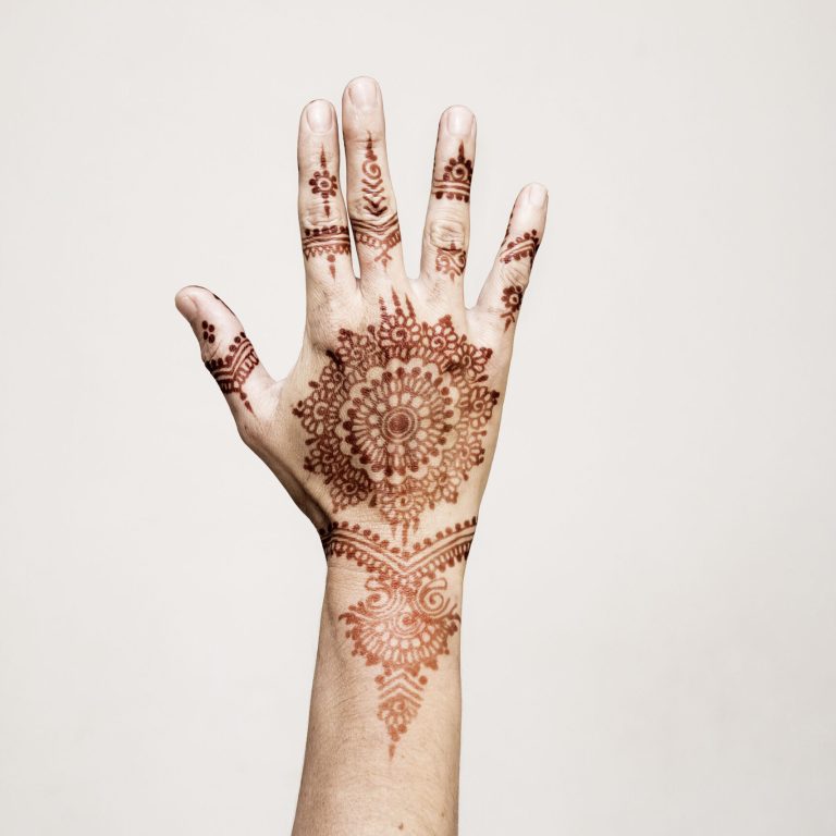 Hand with henna tattoo making gesture